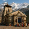 Kedarnath Temple with snow-covered Himalayas in background and devotees gathered in peaceful prayer atmosphere.